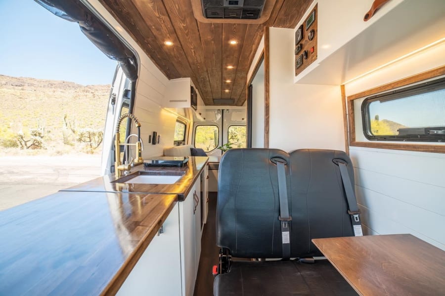 Spacious RV rental with a sleek kitchen, cozy seating, and wooden details, perfect for desert adventures.