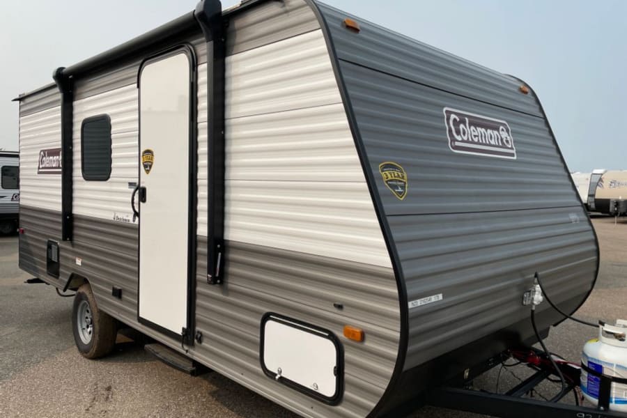 Gray and white Coleman travel trailer for rv rental. This compact camper is ready for outdoor adventures.