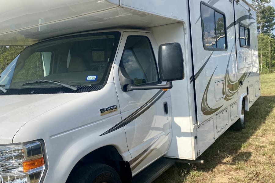 White Sunseeker Class C rv rental, an E-450 motorhome, parked in a sunny grassy field.