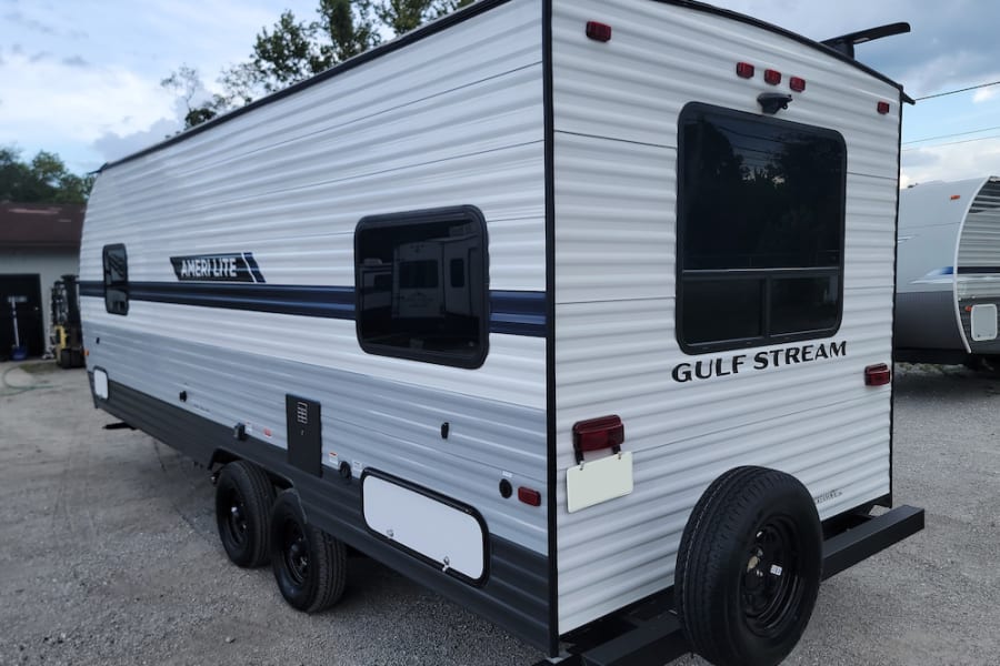 Clean Gulf Stream Ameri-Lite travel trailer, perfect for an RV rental. Side/rear view with spare tire.