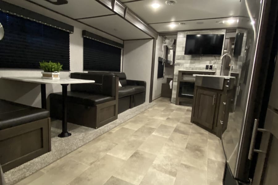 RV rental: Bright, modern travel trailer interior featuring a spacious dinette, sofa, and kitchen.