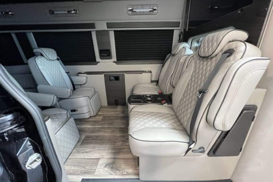 Spacious luxury RV rental interior with plush, light-colored quilted captain's chairs for comfortable travel.