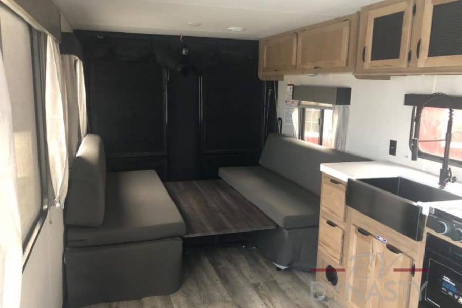 Check out this RV rental's versatile interior with a modern kitchen, convertible bench seating, and dining table.