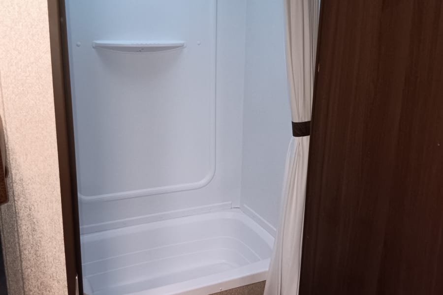 RV rental bathroom: compact shower/tub combo, toilet & skylight.