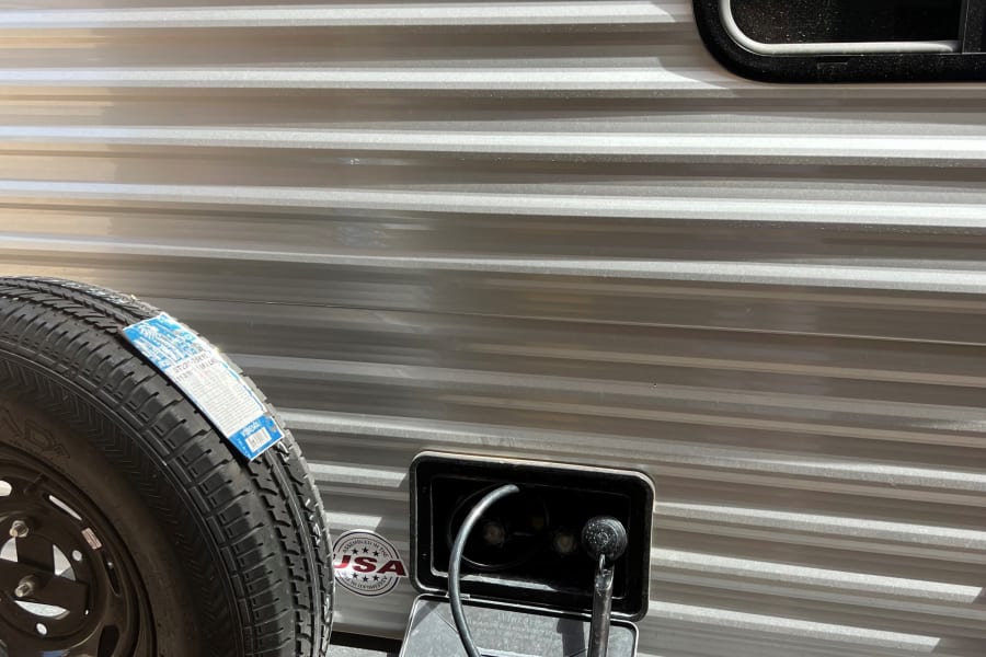 Side of an RV rental showing its Forest River Salem FSX branding, mounted spare tire, and open outdoor shower.