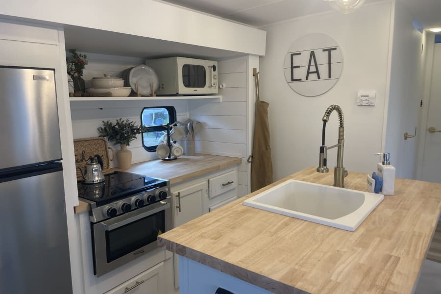Spacious & modern RV rental kitchen with wood counters, stainless appliances, and full amenities. Perfect for your next trip!