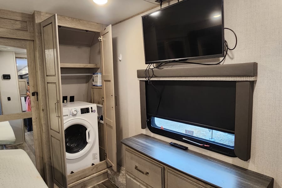 RV rental: Bedroom featuring a convenient washer/dryer combo, dresser, storage, and TV.