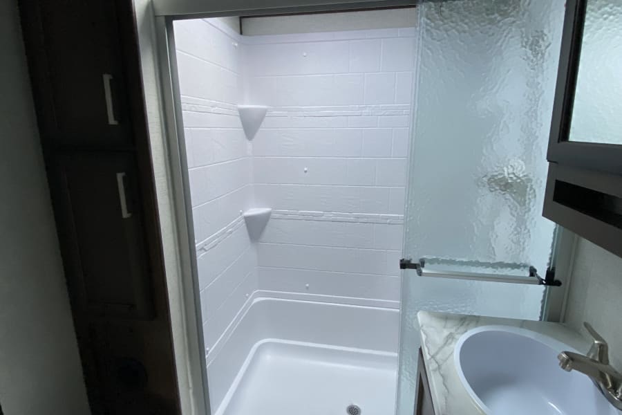 Clean RV rental bathroom featuring a sleek shower, modern sink, and a compact toilet. Perfect for travels.