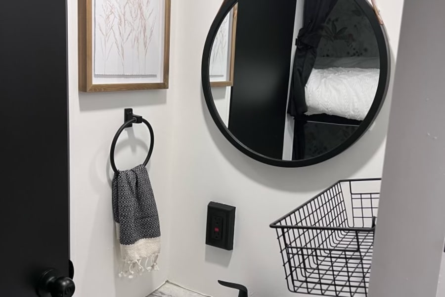 Compact RV rental bathroom with modern black accents. White sink, black faucet, and decorative art create a stylish space.