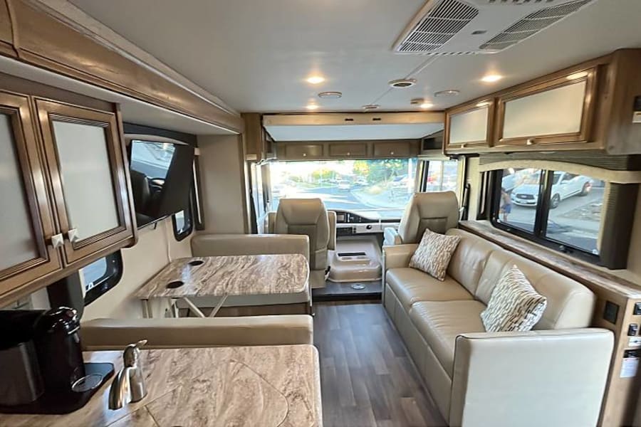 Spacious RV rental interior featuring a comfortable living area, dinette, kitchen space, and front cockpit, perfect for travel.