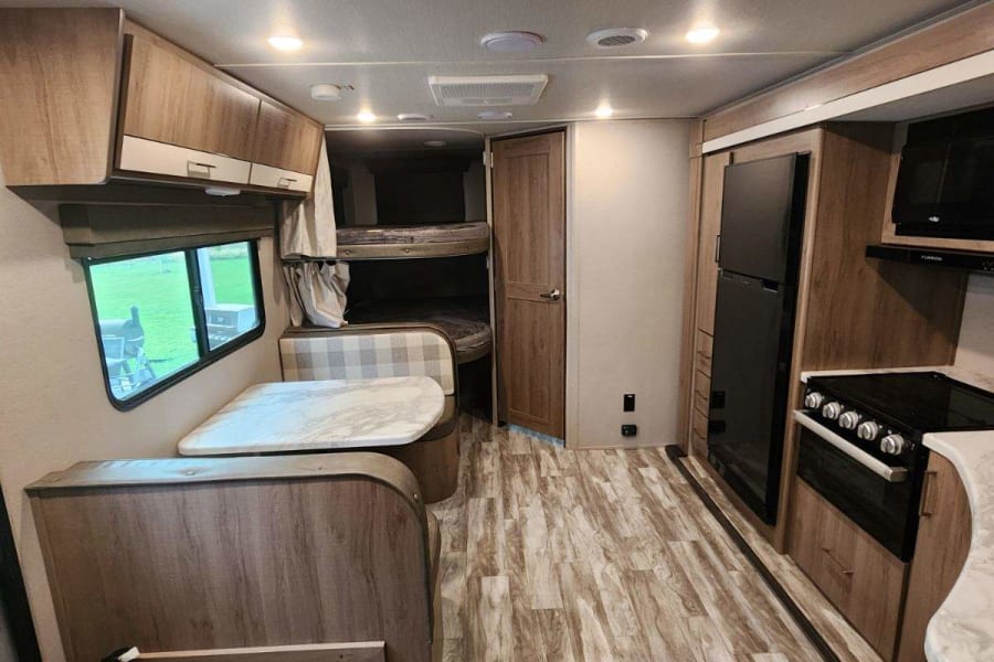 Spacious RV rental interior featuring a dinette, bunk beds, and full kitchen, ideal for family trips.