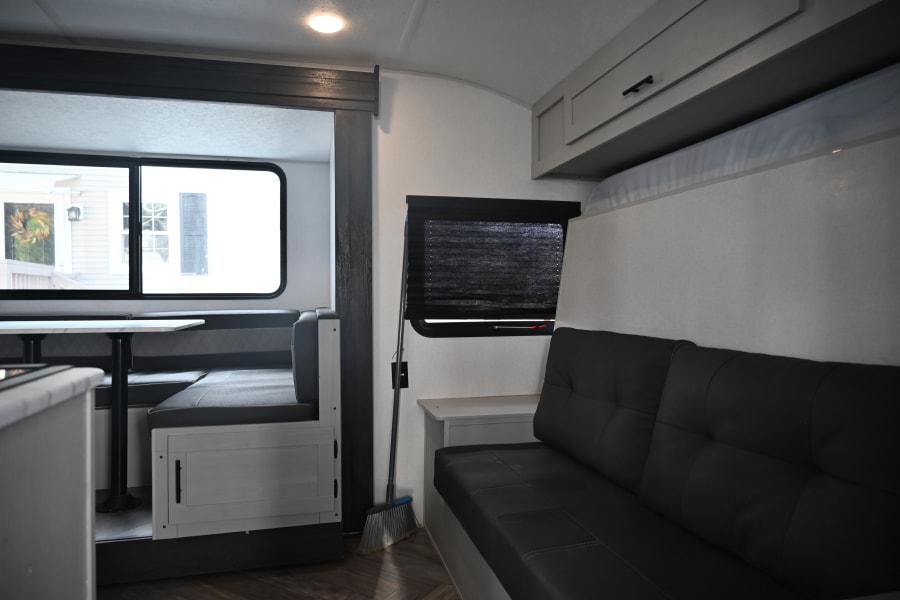 RV rental interior with a bright dinette, comfortable sofa, and overhead cabinets, offering a compact and functional living space.