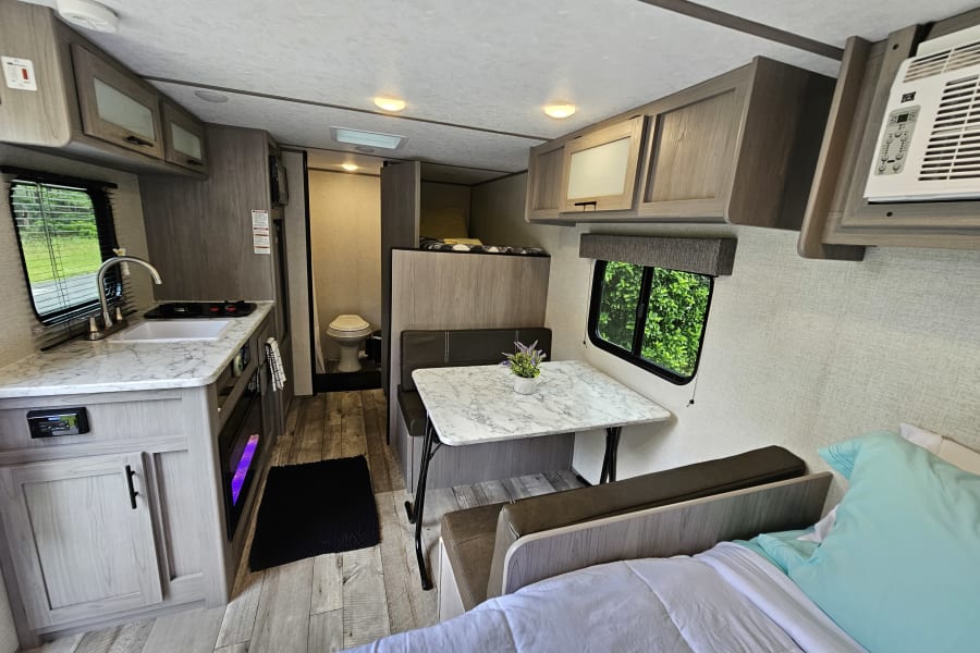 RV rental interior. A well-equipped camper with kitchen, dining, bunk beds, and a small bathroom visible.