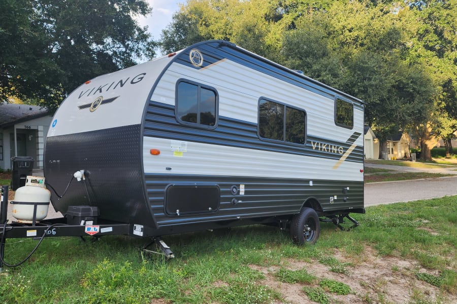 New Viking travel trailer RV rental, light & dark grey with black accents, parked on grass. Perfect for outdoor trips.