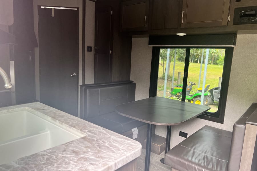 RV rental: Inside a travel trailer featuring a kitchen, dinette, and cabinets, with a clear view out the window.