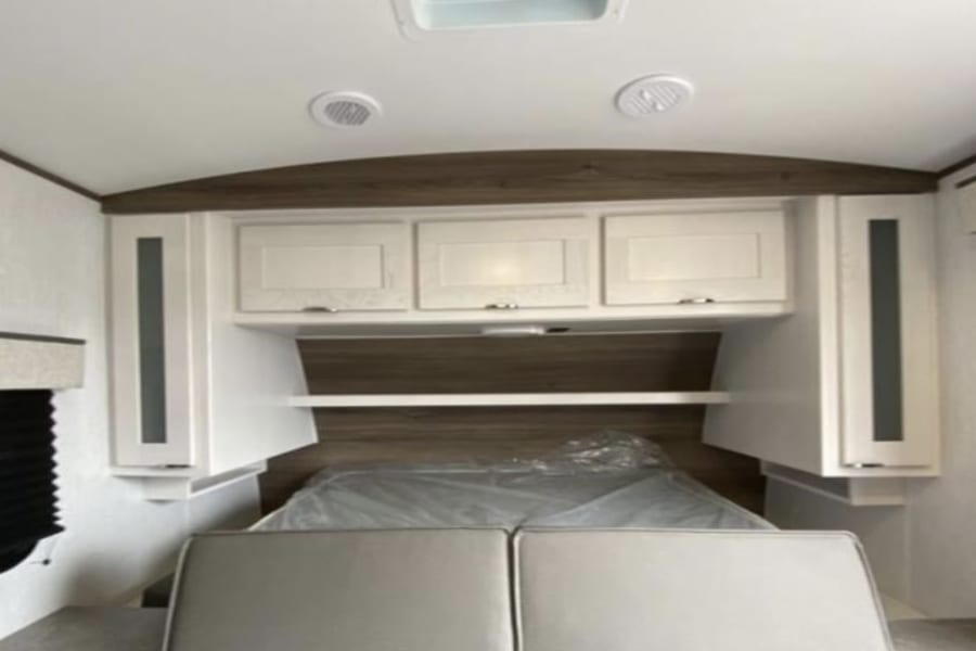 RV rental interior: cozy bedroom with bed, overhead cabinets, and side storage.