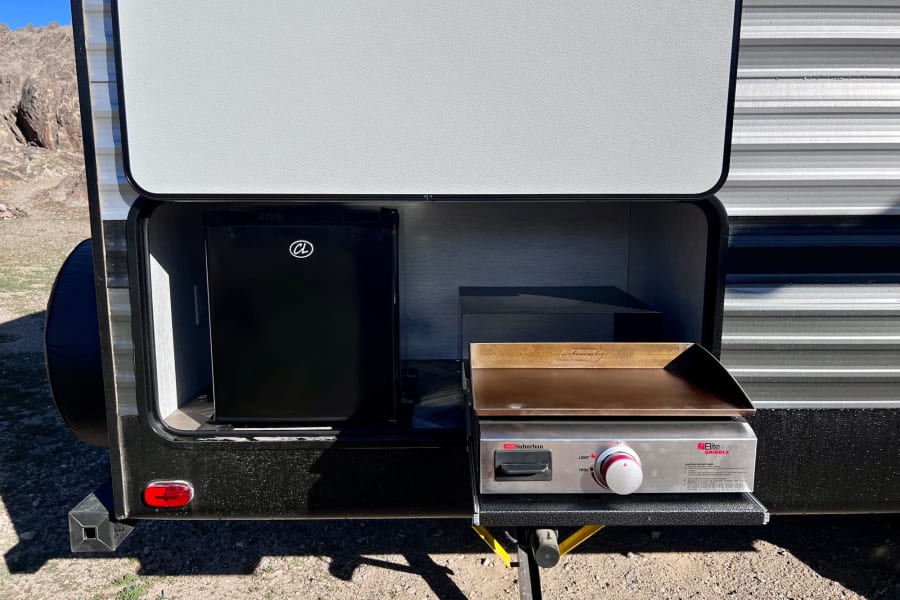 RV rental outdoor kitchen featuring a mini-fridge and pull-out griddle, perfect for camp cooking and outdoor adventure.