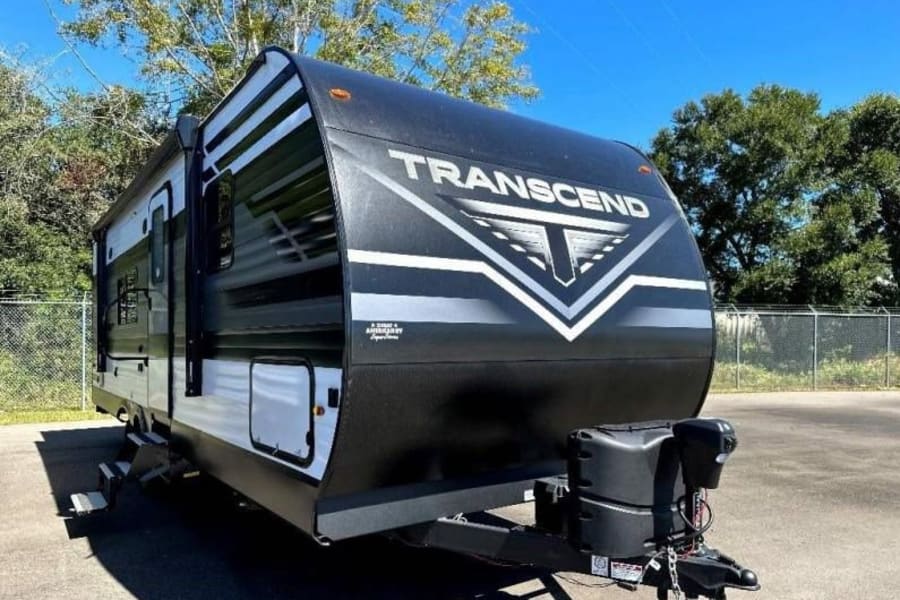 Black and white Transcend travel trailer for rv rental, parked outdoors. Ideal for your next camping adventure.