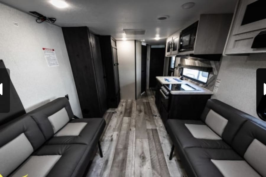 RV rental interior: modern kitchen, comfortable seating, and wood-look flooring. Perfect for your next adventure.