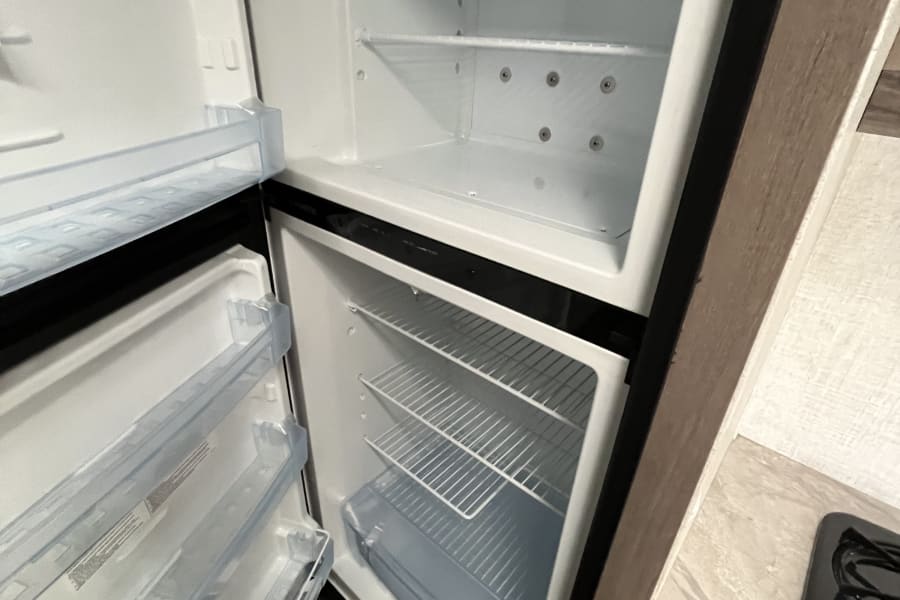 RV rental kitchen: Clean, empty refrigerator and freezer with open doors, ready for your adventure.