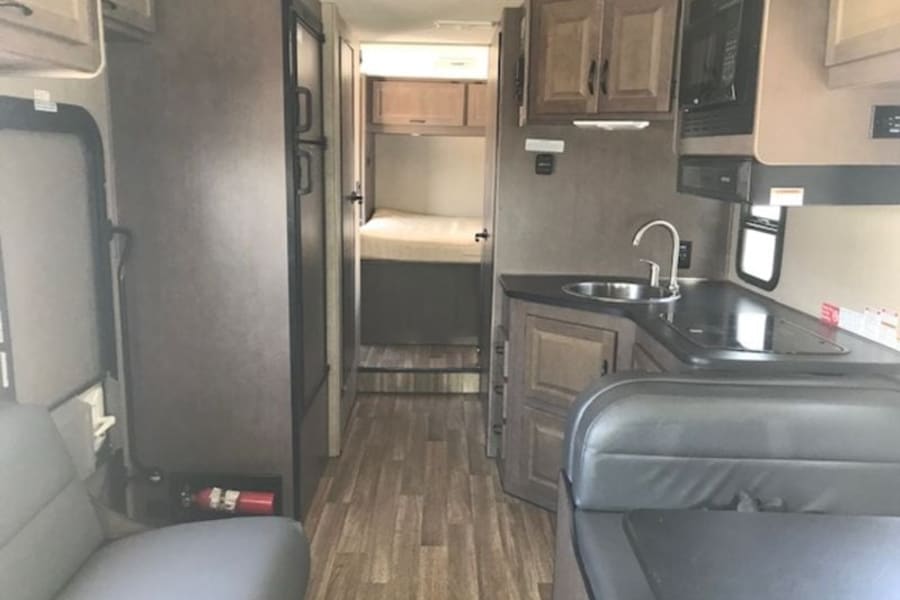 Inside this RV rental: kitchenette, dinette, refrigerator, and rear bed. Your mobile home for travel.
