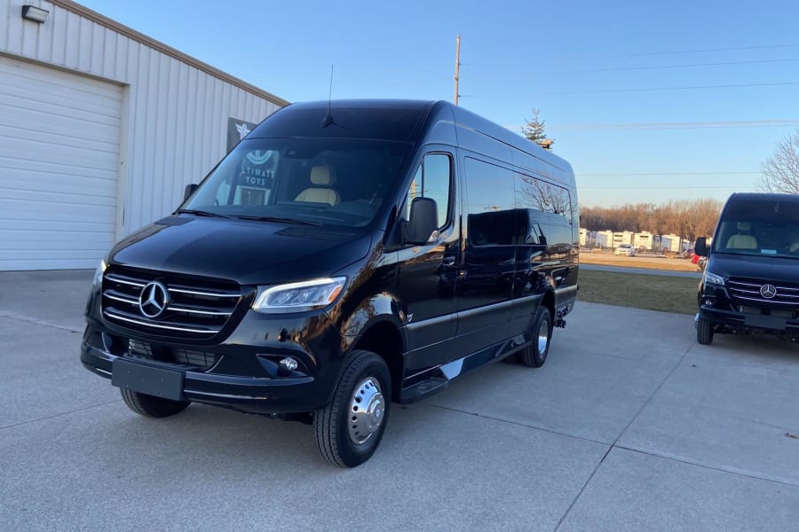 Two black Mercedes-Benz Sprinter vans, ideal for luxury RV rental, parked on a concrete lot.