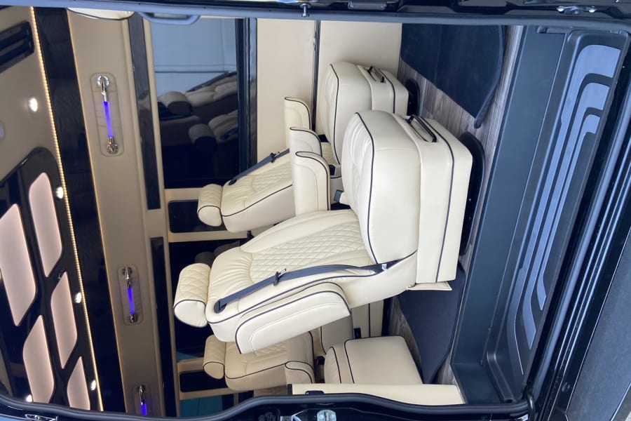 Luxury RV rental interior with plush cream leather seats, black piping, and ambient lighting. Ideal for comfortable travel.