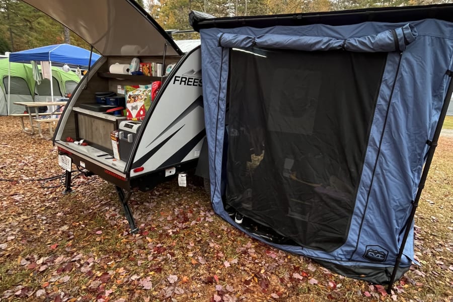 Autumn camping with an rv rental: a compact teardrop trailer featuring an open kitchen and attached screened room.