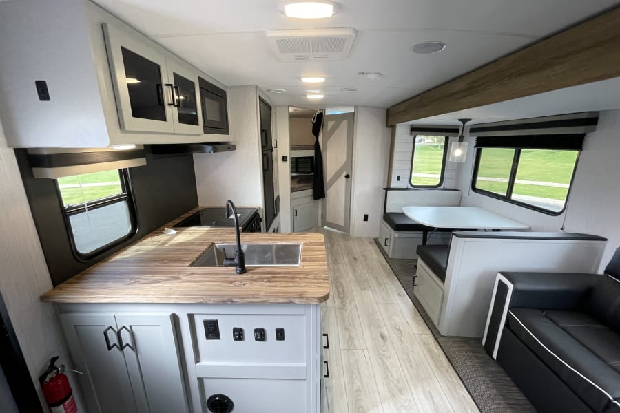 Spacious, modern RV rental interior with a well-equipped kitchen, dining booth, and cozy living area, ideal for travel.