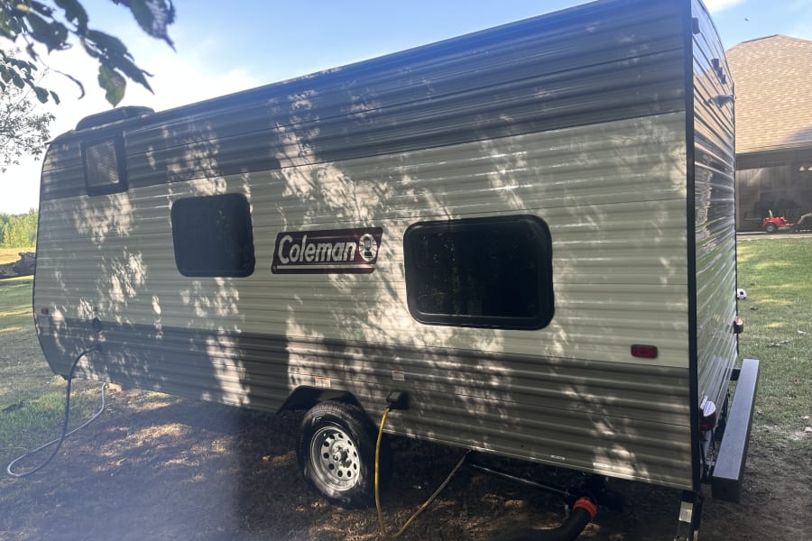 Spacious Coleman RV travel trailer, perfect for your next rv rental adventure. Parked outside with utility hookups.