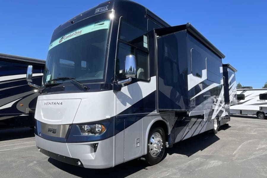 A sleek dark blue & white luxury motorhome, with slides out, perfect for your next rv rental adventure. Travel in comfort!