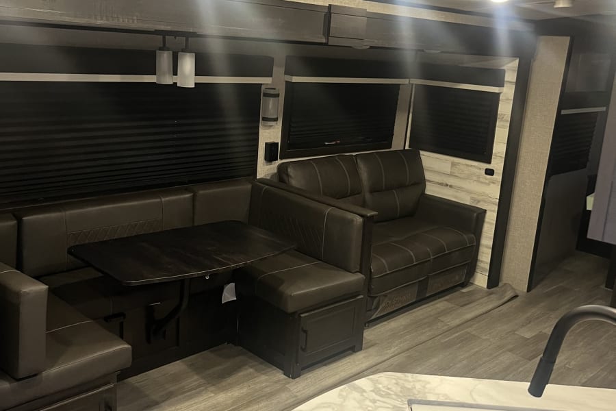 Spacious and modern RV rental interior featuring a comfy dinette, sofa, and kitchen area, perfect for travel.