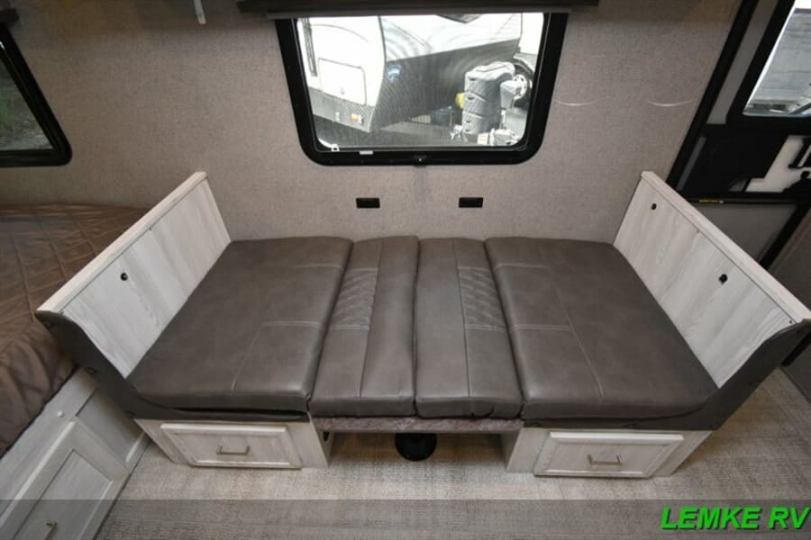 RV rental interior: A gray upholstered dinette with storage drawers, likely converting to a bed. Ideal for compact travel.