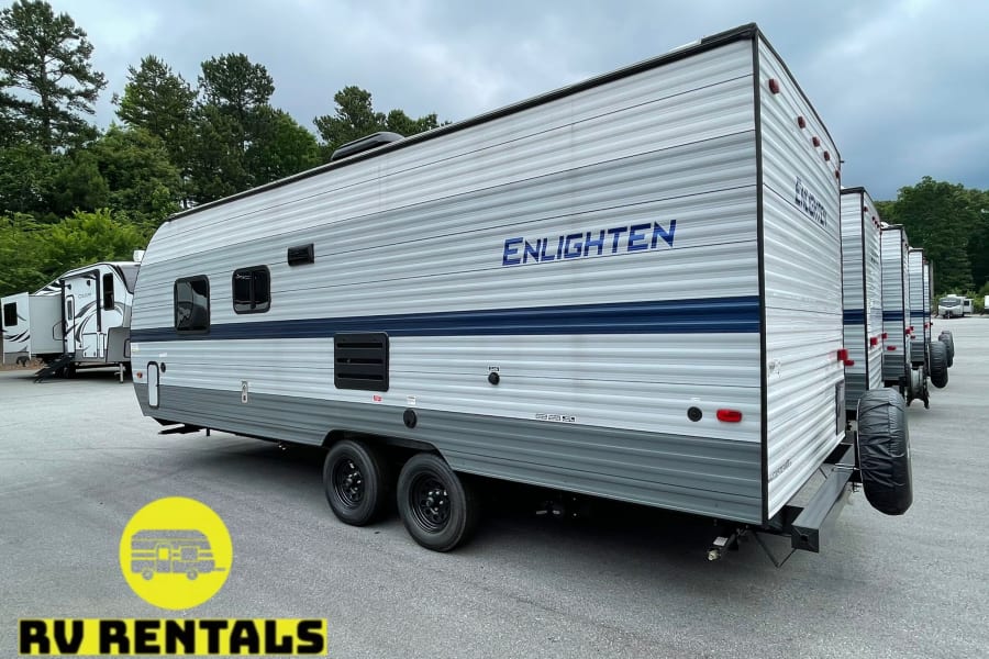 Modern gray travel trailers, like the 'ENLIGHTEN' model, available for RV rental, parked in an outdoor lot.
