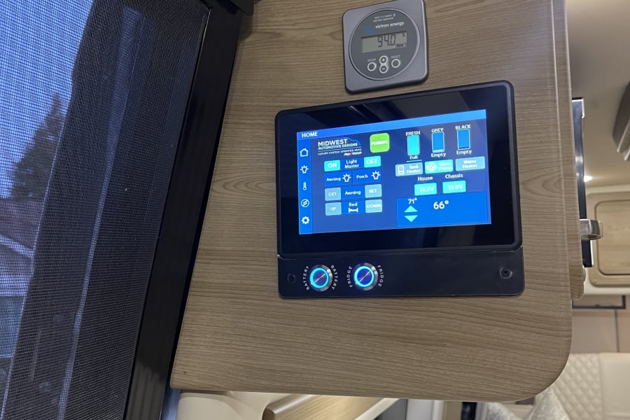 RV rental's control panel: a touchscreen shows 94% battery, water tank levels (fresh, grey, black), and controls for lights & bed.