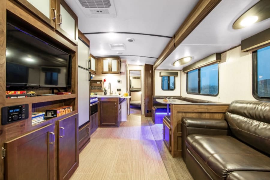 Bright RV rental interior with a cozy living area, well-equipped kitchen, and dining booth. Ideal for travel adventures.