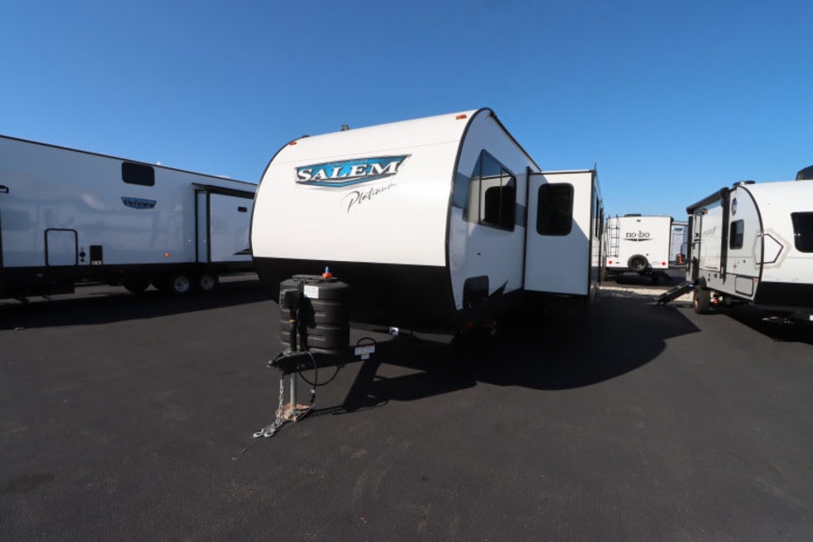 A bright white Salem Platinum travel trailer sits prominently on a sunny RV rental lot, surrounded by other models.