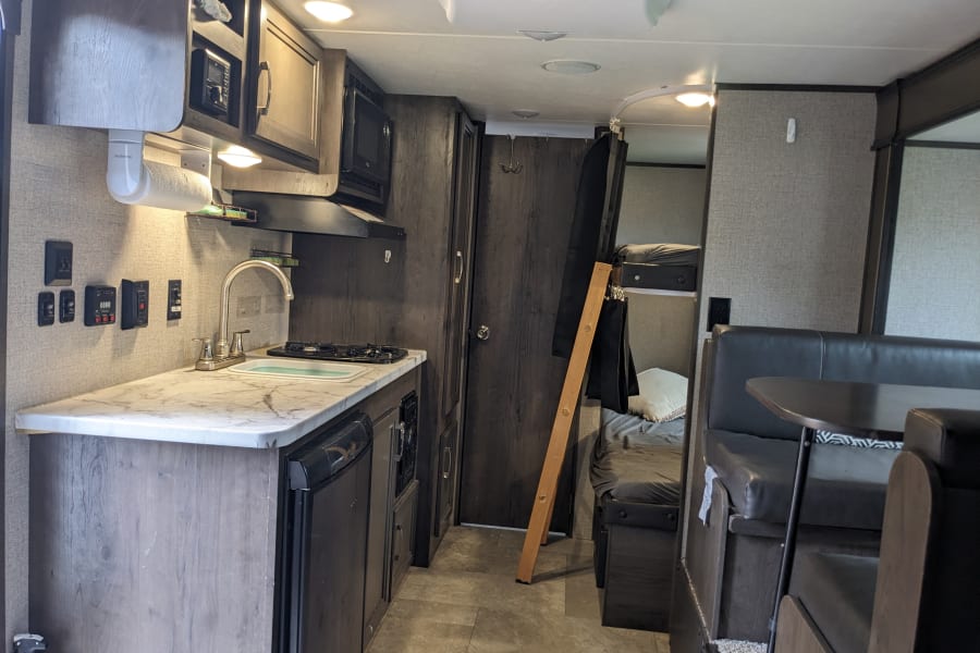 From the queen bed at the front of the camper, looking towards the back. Kitchen on left, dinning room on right, bathroom door straight back, bunk beds beside that. 