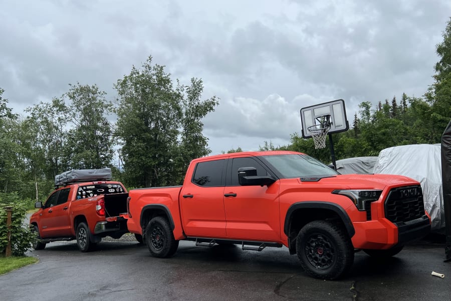 Bright orange Toyota Tundra trucks, one with a rooftop tent, prepped for an outdoor RV rental adventure.