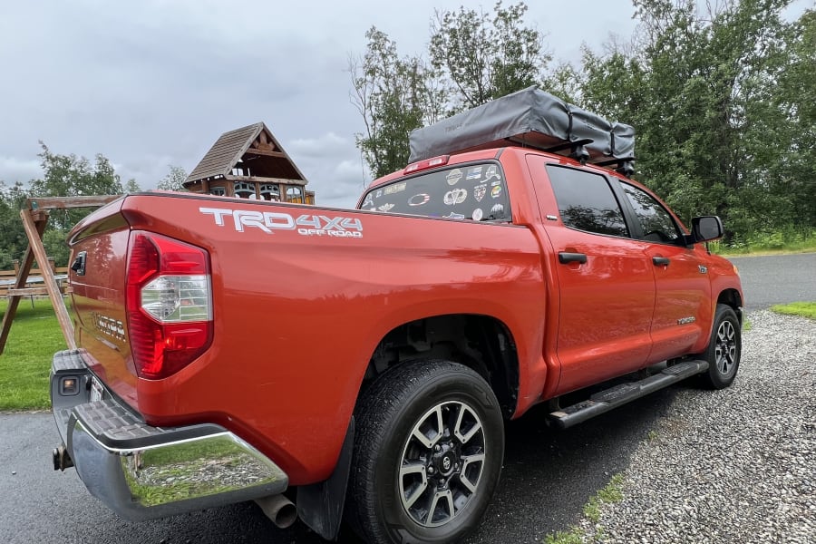 Orange Toyota Tundra 4x4 truck with a rooftop tent. An adventurous alternative to traditional RV rental for camping.