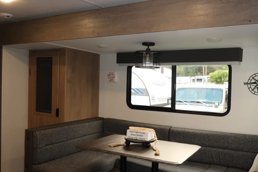 Cozy RV rental interior: a comfortable dinette with U-shaped seating, table, and bright window for your journeys.