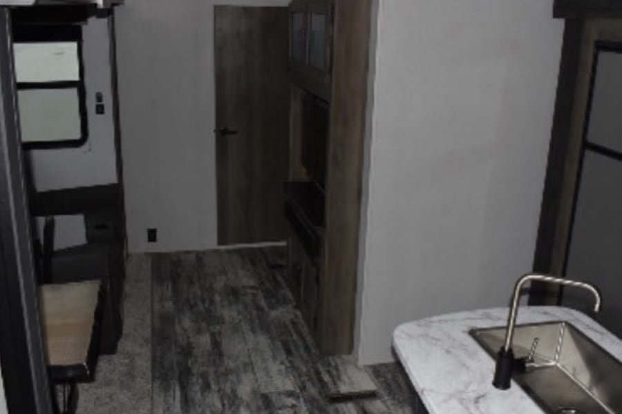 RV rental interior: kitchen, media center, dinette, and door. Modern design, wood-look flooring.