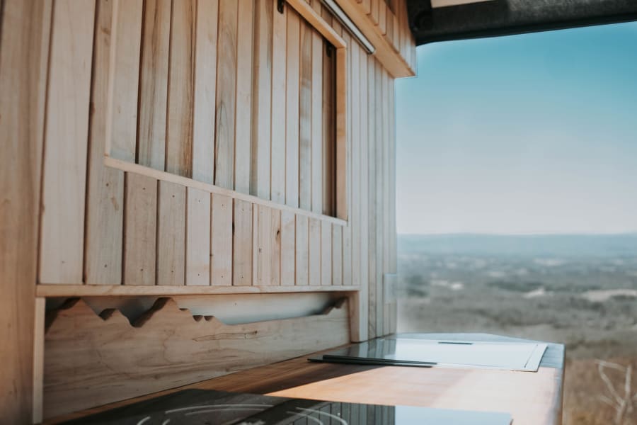 This inviting RV rental features a cozy wood-paneled kitchen with built-in cooktops and a vast mountain view.