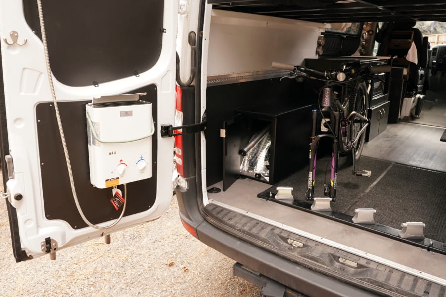 This RV rental van features a rear outdoor shower, portable water heater, and secure interior bike storage.