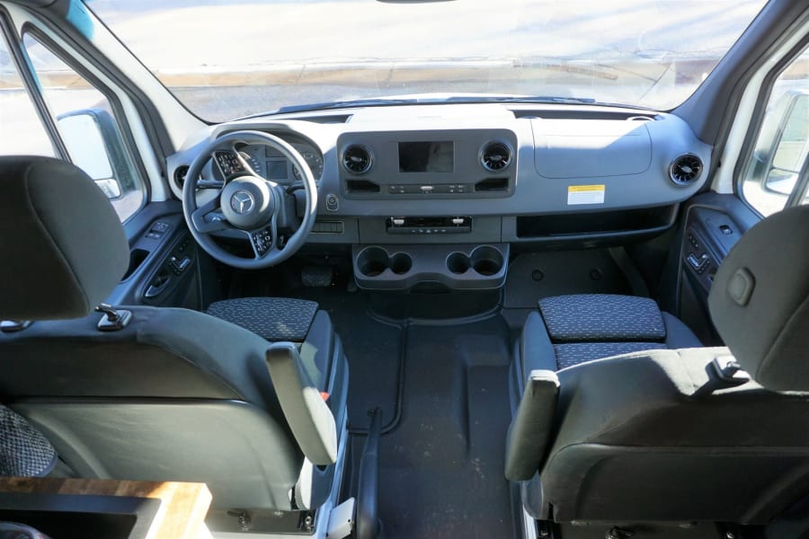 Detailed rv rental van interior. View of front seats, dashboard, and steering wheel, ready for your next adventure.