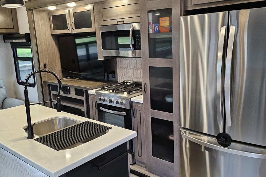 Modern RV rental kitchen with stainless steel appliances, a spacious island sink, and elegant lighting for comfortable travel.