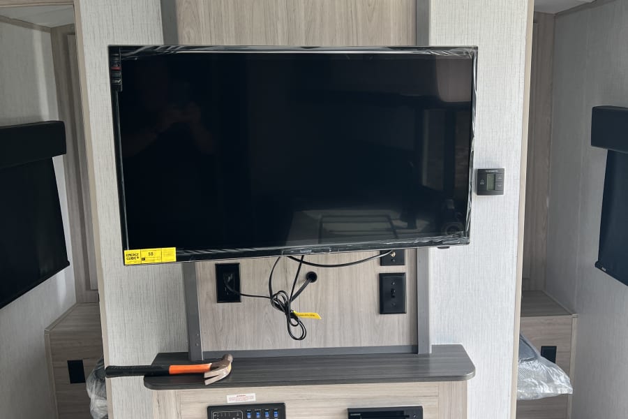 RV rental interior: Entertainment center with a new TV, electric fireplace, and user control panels for comfort.