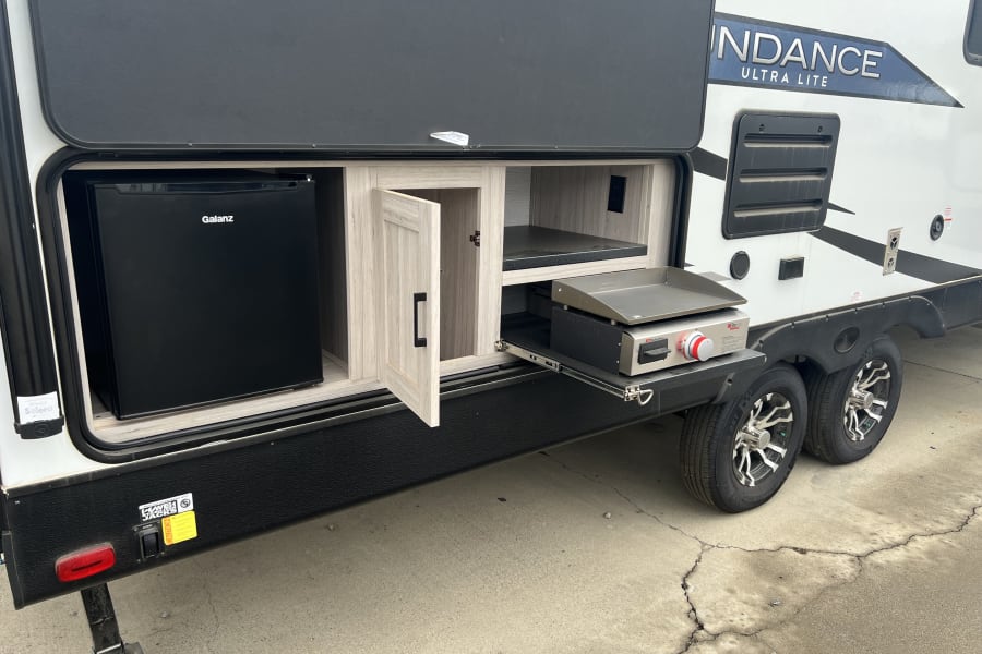 This RV rental's outdoor kitchen setup includes a Galanz mini-fridge and pull-out griddle, ideal for convenient camping.