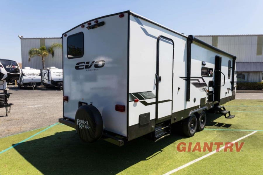 This white Forest River EVO travel trailer is ready for your next rv rental adventure, parked on green turf.