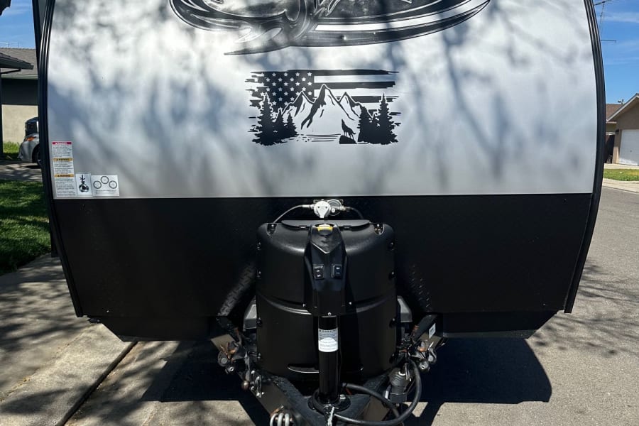 Get ready for camping! This Wolf Pup travel trailer, an ideal RV rental, features its front with a striking wolf logo and essential hitch equipment.
